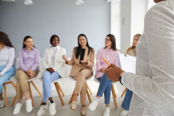 Female coach meeting with a team of young diverse women. Close up of a woman's hand holding a...