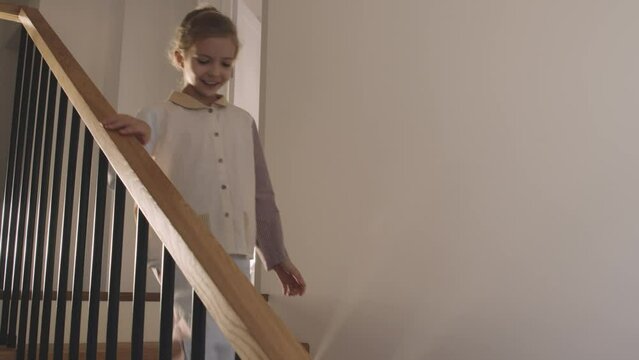 Slow motion shot footage of cheerful Caucasian girl wearing pyjamas rushing going downstairs