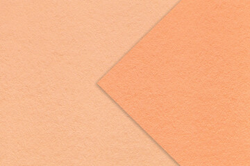 Color of the year 2024. Texture of peach fuzz paper background, half two colors with coral arrow, macro.