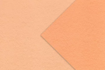 Color of the year 2024. Texture of peach fuzz paper background, half two colors with coral arrow, macro.