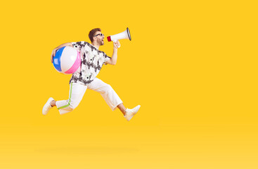 Portrait of a funny young man tourist wearing casual clothes with inflatable beach ball screaming in mouthpiece on studio yellow background and jumping. Vacation trip and summer holiday concept. - obrazy, fototapety, plakaty