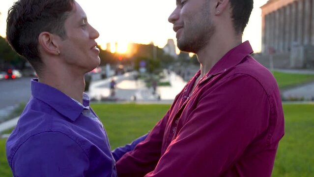 Two latin gay students hugging and kissing tenderly outside university in Golden Light. Slow motion.