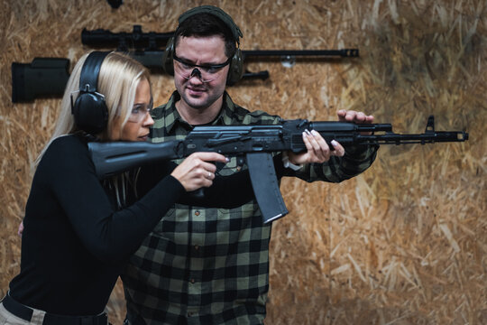 A young beautiful girl with an instructor learns to shoot from an AK74m rifle.