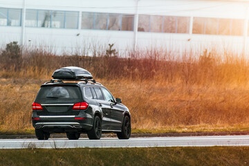 Expensive family SUV with Luggage box mounted on the roof. Extra Capacity for the Road. Black SUV...