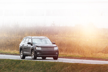 modern family SUV car journeys along a scenic road with majestic nature and a golden sunset in the...