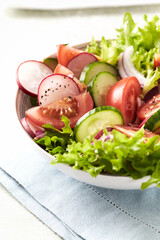 Healthy Salad with Tomatoes, Radish and Lettuce. Easy summer snack. Bright wooden background. Copy space.	