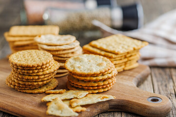 A stack of crackers neatly arranged on cutting board on wooden tabletop.