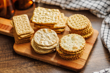 A stack of crackers neatly arranged on cutting board on wooden tabletop.