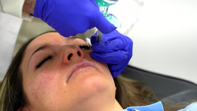 Doctor injecting hyaluronic acid injection to the face of a woman during a rejuvenation beauty procedure