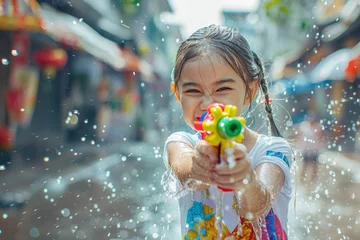 Foto op Plexiglas Happy traveler asian girl wearing summer shirt holding colourful squirt water gun over blur city, Water festival holiday concept © grapestock
