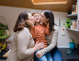 Couple of two lesbian mothers giving a kiss to their son