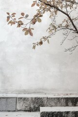 Autumn leaves on a branch against a textured white wall with copy space.