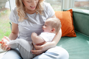 A 5-month-old baby and his  beautiful blonde mom relax, play and laugh in the living room. People a...