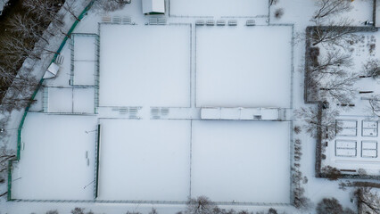 Drone photography of tennis courts covered by snow in a city public park during winter day