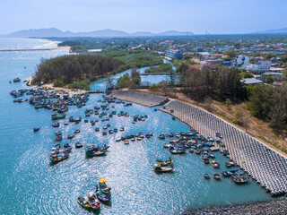 Aerial view of Loc An fishing village, Vung Tau city. A fishing port with tsunami protection concrete blocks. Cityscape and traditional boats in the sea.