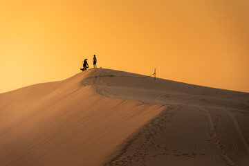 Aerial view of a peasant woman carries a bamboo frame on the shoulder across sand dunes in Ninh...