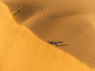 Aerial view of a peasant woman carries a bamboo frame on the shoulder across sand dunes in Ninh...