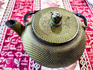 Traditional Cast Iron Teapot on an Oriental Rug. Cast iron teapot poised on a richly patterned rug