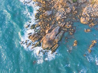 Aerial drone top view of beautiful waves crashing on the rocky island coast, ocean waves and...
