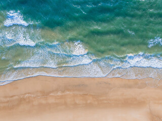 Ocean waves on the beach as a background. Aerial top down view of beach and sea with blue water...
