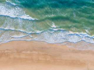 Ocean waves on the beach as a background. Aerial top down view of beach and sea with blue water...