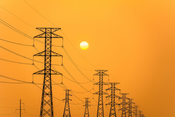 Electricity pillars against a colorful yellow sunset. Silhouette high voltage electric towers,...