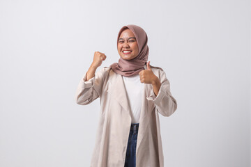 Portrait of attractive Asian hijab woman in casual suit making thumb up hand gesture, saying good job. Businesswoman concept. Isolated image on white background