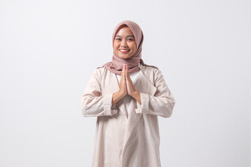 Portrait of excited Asian hijab woman in casual suit showing apologize and welcome hand gesture....