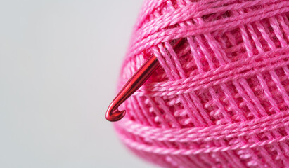 Close-up view of skein of pink cotton yarn and metal crochet hook. Empty space for text on the left on white background. DIY concept. Crochet as a hobby. Flat lay, copy space, top view, macro