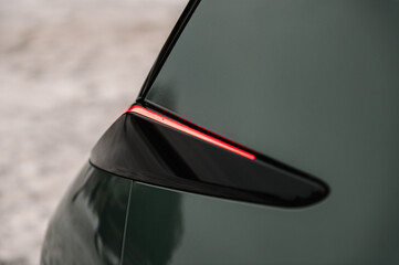 Red tail lights closeup. The left rear light shining on a new modern electric sedan car. Modern...