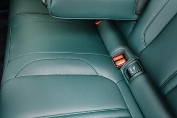 Installing ISOFIX baby and car seat for maximum safety. Part of green perforated leather car seat....