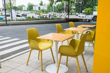 Yellow steel chairs and tables near street in city, empty with nobody using the area,restaurant or cafe. - obrazy, fototapety, plakaty