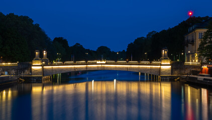 The illuminated Stadsbron bridge over the river Lidan in Lidkoping in blue hour lighting and colorful reflections