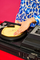 Young stylish woman, dj using sound mixer with pancake instead of vinyl record on pink background....