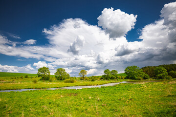 Breathtaking countryside with green meadows and river on a summer sunny day.