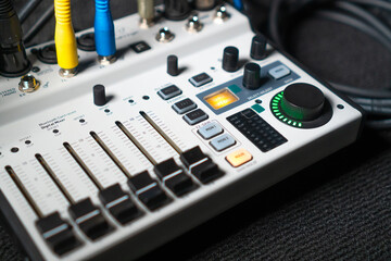 Close-up image of hand adjusting mixer knob for volume control during live studio performance. Mixer features multiple knobs and buttons for precise audio mix adjustments. - obrazy, fototapety, plakaty