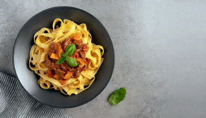 Pasta fettuccine with beef ragout sauce in a black bowl - obrazy, fototapety, plakaty