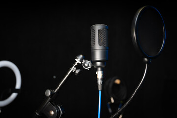 Close-up of a professional condenser studio microphone on a black background in a music studio.