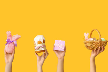 Female hands holding Easter cake with basket and gifts on yellow background