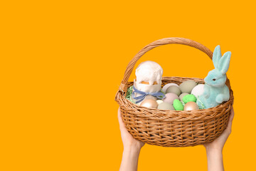 Female hands holding basket for Easter on yellow background