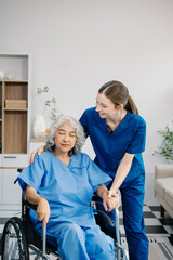 Nurse helping elderly woman walk in the room, holding his hand, supporting. Treatment and rehabilitation after injury in assisted living facility, senior care .