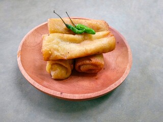 risol, traditional Indonesian food made from chicken and vegetables wrapped in flour dough served on a wooden plate on a gray background. fried food. rissoles