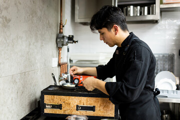 A young Mexican chef is cooking inside a modern restaurant kitchen.The Latin man is making a...