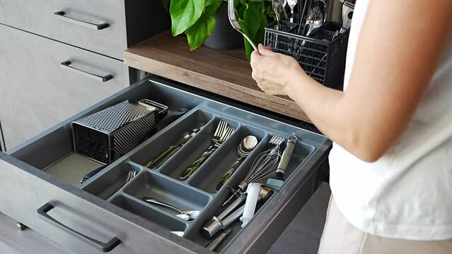 Housewife hands tidying up cutlery after dishwasher machine. Woman neatly assembling fork, spoon, knife accessories for storage organization 