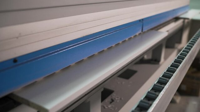 Machine for gluing tape on MDF panels. Technological material for gluing chipboard edges. The MDF panel is fed to a furniture production machine. A veneer machine at a woodworking factory.