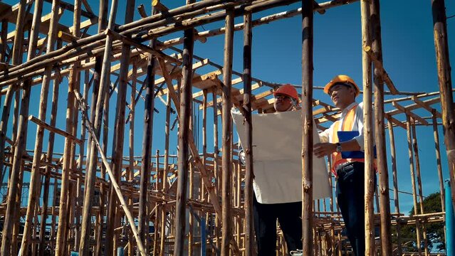 Structural engineer or architect and foreman worker with blueprints discuss, plan working for the outdoors building construction site. 4K