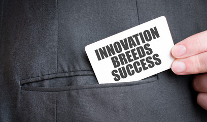 Business card with Innovation Breeds Success text being placed into a pocket. Business identity and...