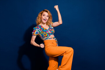 Portrait of nice young lady raise fists empty space wear top isolated on dark blue color background