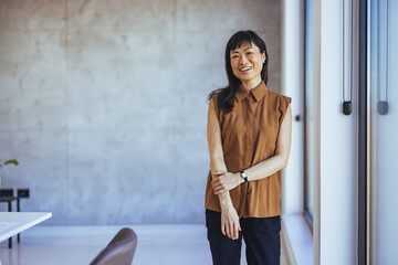 Portrait Of Female Designer Standing In Modern Office. Confident young Asian businesswoman standing...