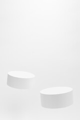 Abstract scene - two round tilt white tilt podiums for cosmetic products mockup, fly on white background. For presentation skin care products, gifts, goods, advertising, showing in minimal style.